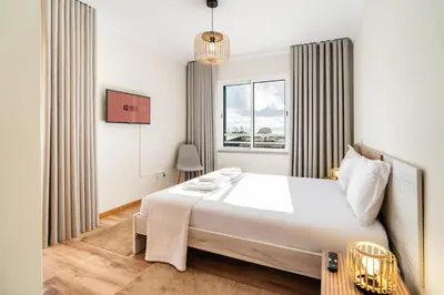 a bedroom with a large white bed and a window at GuestReady- Charming Condo with Pool in Caniço in Caniço