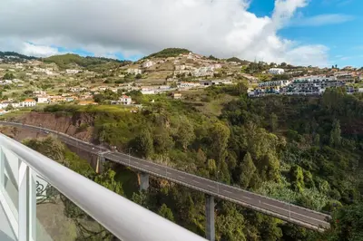 a bridge over a mountain with houses on a hill at GuestReady- Charming Condo with Pool in Caniço in Caniço