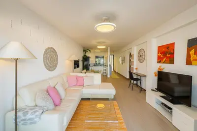 a living room with a white couch and a flat screen tv at Varandas do Sol - Private Sun Terrace close to Natural Pools & Praia Formosa in Funchal