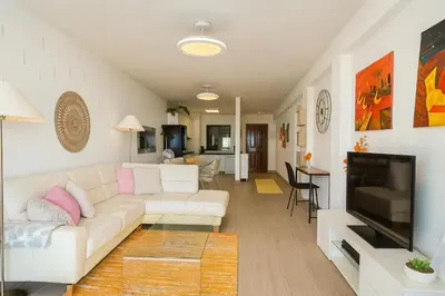 a living room with a white couch and a television at Varandas do Sol - Private Sun Terrace close to Natural Pools & Praia Formosa in Funchal