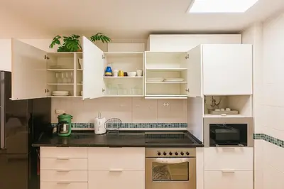 a kitchen with white cabinets and black counter tops at Varandas do Sol - Private Sun Terrace close to Natural Pools & Praia Formosa in Funchal
