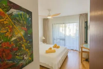 two yellow towels on a bed in a room with a painting at Varandas do Sol - Private Sun Terrace close to Natural Pools & Praia Formosa in Funchal