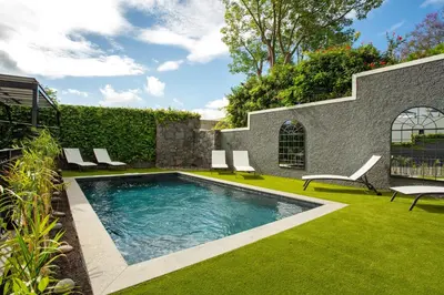 a swimming pool with two chairs next to a house at Vila Francisco in Funchal