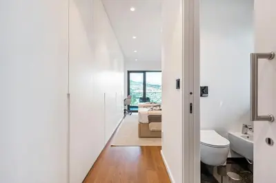a white bathroom with a toilet and a bed at Panoramic Bay and Sea Views - Luxury 3-Bed Flat in Funchal
