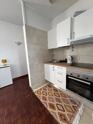 a kitchen with white cabinets and a rug on the floor at América Apartment Holiday in Funchal