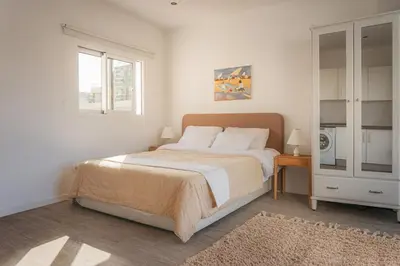 a white bedroom with a large bed and a window at Madeira Rooftop Studio, Ocean & City View in Funchal
