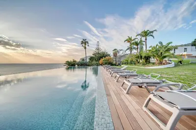 a pool with lounge chairs next to the ocean at In-Town Residences in Funchal