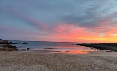 a sunset on a beach with the ocean at Casa da Ingrina in Raposeira