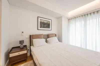 a white bedroom with a bed and a window at Acqua Residence in Funchal