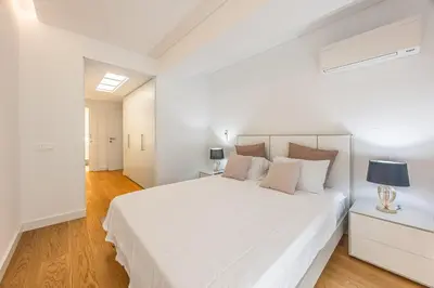 a white bedroom with a large white bed and a lamp at Acqua Residence in Funchal