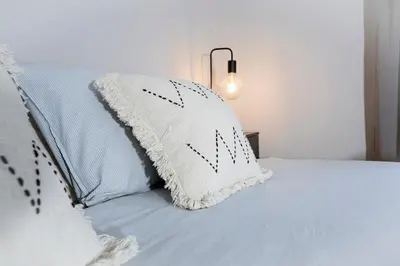 a white pillow on a bed with a lamp at Orteá Sea Breeze in Budens