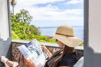 a woman wearing a hat reading a magazine at Casa da Fonte by YOUR KEY - 1st floor house in Ribeira Brava