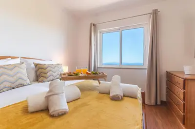 a bedroom with a large bed with a window at My Home Reis Magos by Atlantic Holiday in Caniço