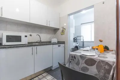 a white kitchen with a table and a microwave at My Home Reis Magos by Atlantic Holiday in Caniço