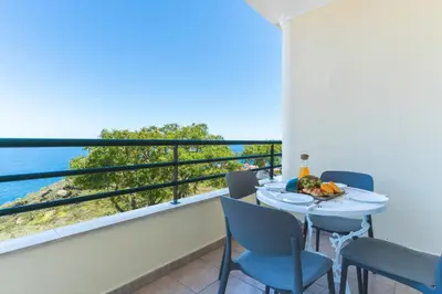 a balcony with a table and chairs and a view of the ocean at My Home Reis Magos by Atlantic Holiday in Caniço