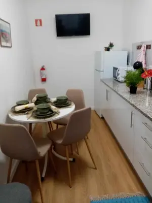 a kitchen with a small table with chairs and a refrigerator at Vivenda Silva in Seixal
