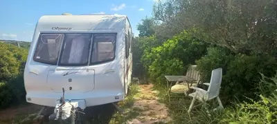a white camper with a table and a chair at Pauls Mobile Home in Baro de So Joo, Portugal in Barão de São João