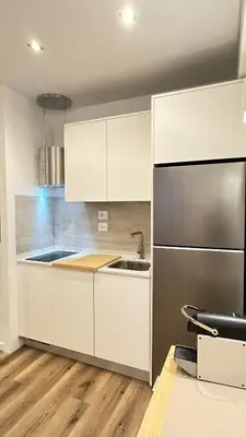 a kitchen with white cabinets and a stainless steel refrigerator at Se Urban Suite 22 in Funchal