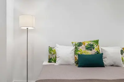 a bedroom with a bed with pillows and a lamp at Funchal Tropical - Filodendro by Homie in Funchal