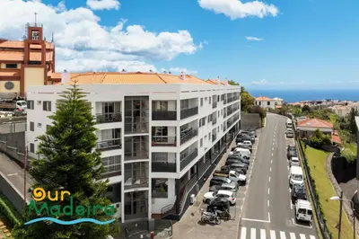 a white apartment building next to a parking lot at OurMadeira - Alamos UpTown in Funchal