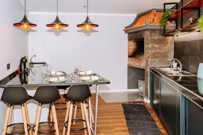 a kitchen with a counter with stools and a table at Dark Yellow in Ponta do Sol