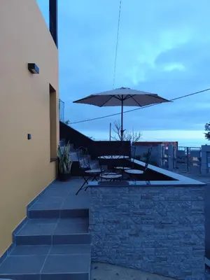 a patio with a table and an umbrella at Dark Yellow in Ponta do Sol