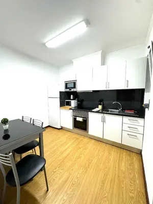 a kitchen with white cabinets and a table and chairs at Apartmento Centro Funchal in Funchal