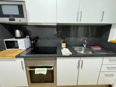 a kitchen with white cabinets and a sink and a microwave at Apartmento Centro Funchal in Funchal