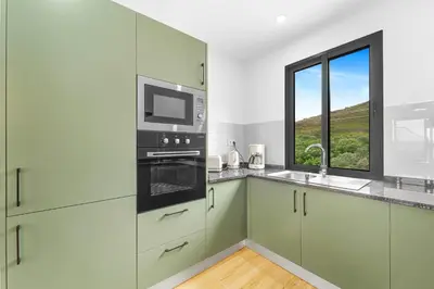 a kitchen and living room with a table and a couch at Casa da Guida in Machico