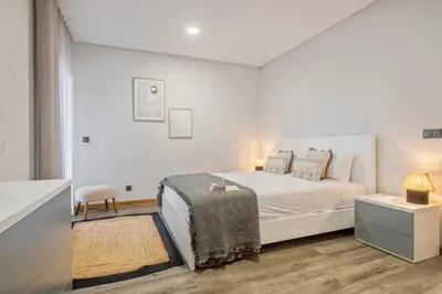 a white bedroom with a bed and a table at Casa das Raposinhas VI, Funchal in Funchal