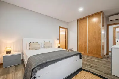 a bedroom with a large white bed and wooden floors at Casa das Raposinhas VI, Funchal in Funchal