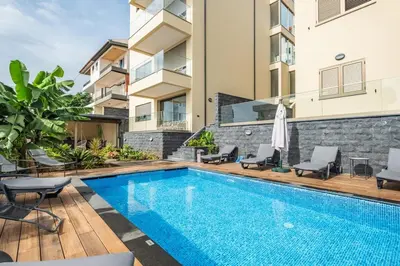 an image of a swimming pool with chairs and a building at Casa das Raposinhas VI, Funchal in Funchal