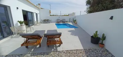 a swimming pool with two lounge chairs next to a house at villa blue mango in Sagres