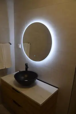 a bathroom with a sink and a round mirror at Vista dos Encantos in Machico