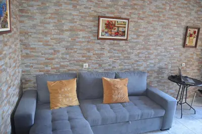 a blue couch against a brick wall with two pillows at Vista dos Encantos in Machico