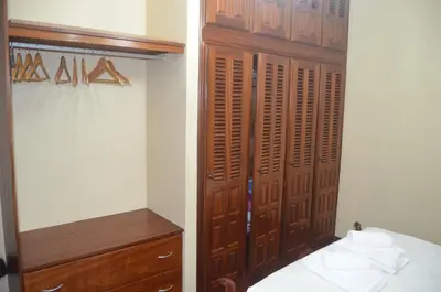 a bedroom with a closet with a bed and a wooden cabinet at Vista dos Encantos in Machico