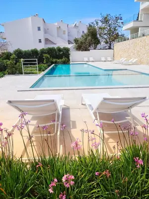 a swimming pool with white umbrellas in front of a villa at Paraíso Florido by the sea in Luz