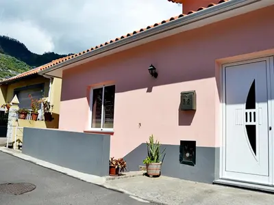 a pink house with a white door at Casa Annie in Arco da Calheta