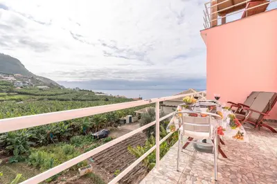 a balcony of a house with a table and chairs at Casa Annie in Arco da Calheta