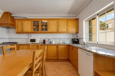 a kitchen with wooden cabinets and a wooden table at Spacious Villa - Walk to Beach & City Center in Lagos