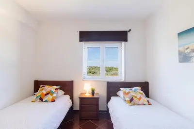 two twin beds in a room with a window at Sunny House in Sagres