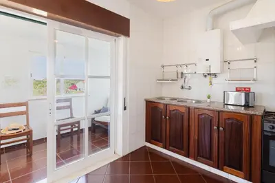a kitchen with wooden cabinets and a large window at Sunny House in Sagres
