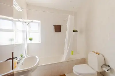 a white bathroom with a tub and a toilet and a sink at Sunny House in Sagres