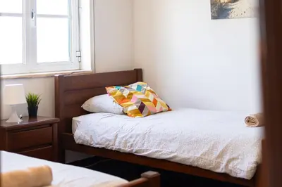 a small bedroom with two beds and a window at Sunny House in Sagres