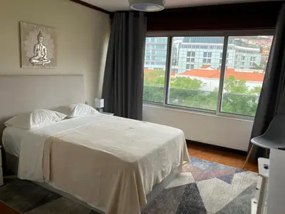 a bedroom with a bed and a large window at Vista Montanha Funchal in Funchal