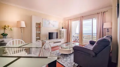 a living room with a table and a couch and a television at Madeira Residence in Funchal
