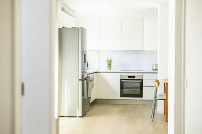 a kitchen with white cabinets and a refrigerator at Green House Beach Side Oasis in Vila Baleira