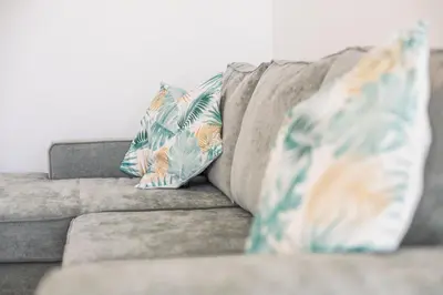 a gray couch with two pillows on it at Green House Beach Side Oasis in Vila Baleira