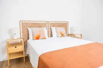 a bedroom with a large bed with an orange blanket at Green House Beach Side Oasis in Vila Baleira