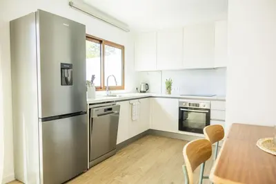 a kitchen with a stainless steel refrigerator and a table at Green House Beach Side Oasis in Vila Baleira